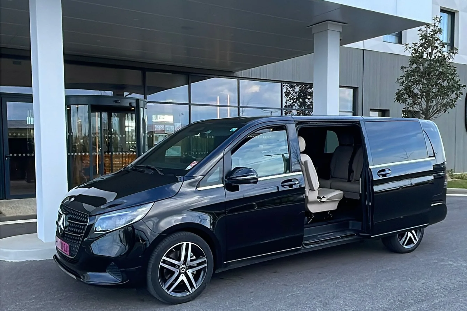 Van Mercedes Classe V portière ouverte devant l'entrée d'un hôtel